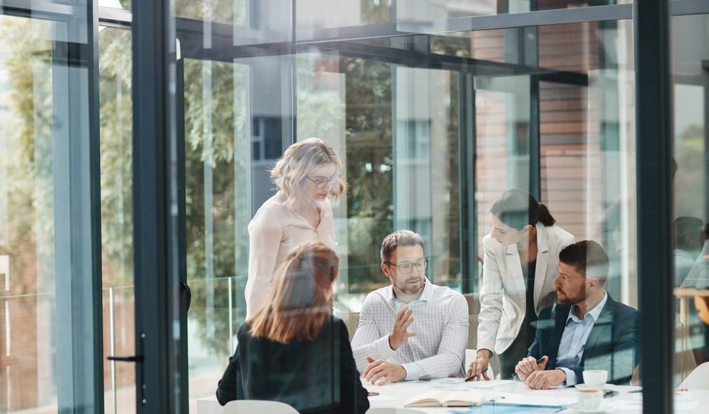 Zespół analityków pracuje przy komputerach w przeszklonym biurze